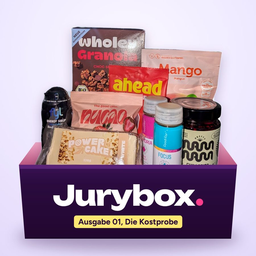 Geöffnete Jurybox Kostprobe mit Granola, Fruchtgummis, Trockenmango, Schokolade, Energy-Sirup, Power Cake, Drink-Shots und Chili Crisp